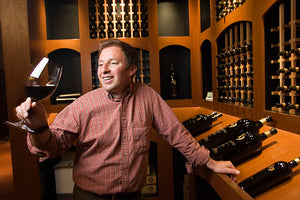 Middle aged man holding a wine glass inside of a wine cellar